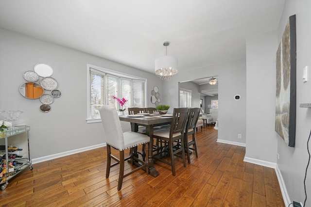 dining room with baseboards, ceiling fan with notable chandelier, and hardwood / wood-style floors