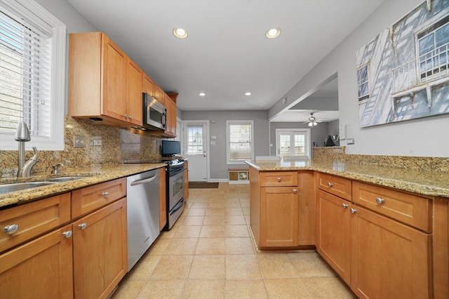 kitchen with recessed lighting, tasteful backsplash, light stone counters, a sink, and appliances with stainless steel finishes