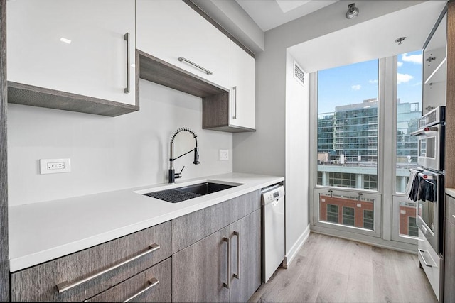 345 N La Salle Dr Unit 2501, Chicago, IL 60654 - kitchen with white cabinets, light wood finished floors, light countertops, dishwashing machine, and a sink