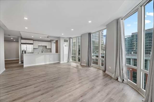 345 N La Salle Dr Unit 2501, Chicago, IL 60654 - unfurnished living room featuring baseboards, recessed lighting, light wood-style floors, and a sink