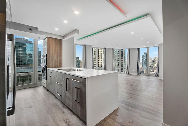 345 N La Salle Dr Unit 2501, Chicago, IL 60654 - kitchen featuring a city view, light countertops, modern cabinets, light wood-type flooring, and black electric stovetop