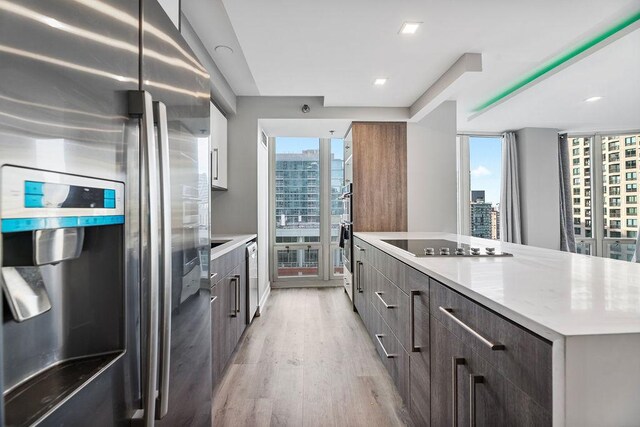 345 N La Salle Dr Unit 2501, Chicago, IL 60654 - kitchen with light wood-type flooring, modern cabinets, black electric stovetop, a city view, and stainless steel refrigerator with ice dispenser