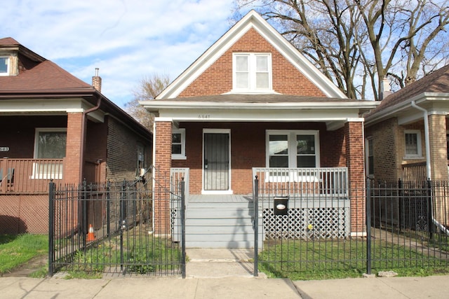 view of front of home featuring a porch, brick siding, and a fenced front yard