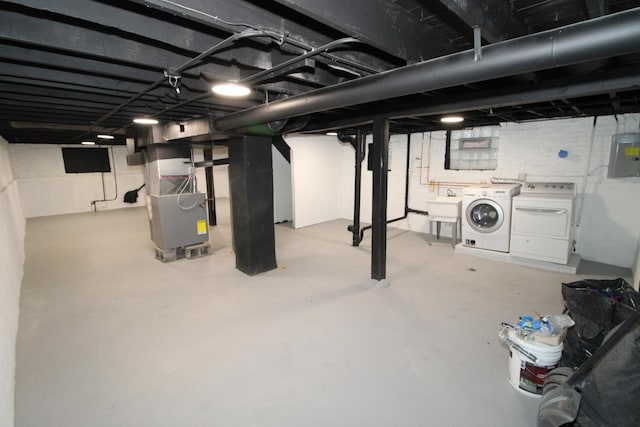 basement featuring independent washer and dryer, electric panel, a sink, and heating unit