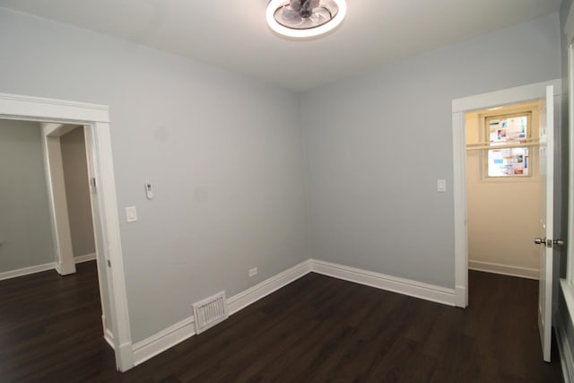 spare room featuring dark wood-style flooring and baseboards