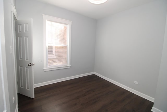 empty room featuring dark wood-type flooring and baseboards