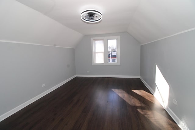 additional living space with dark wood-style flooring, baseboards, and vaulted ceiling