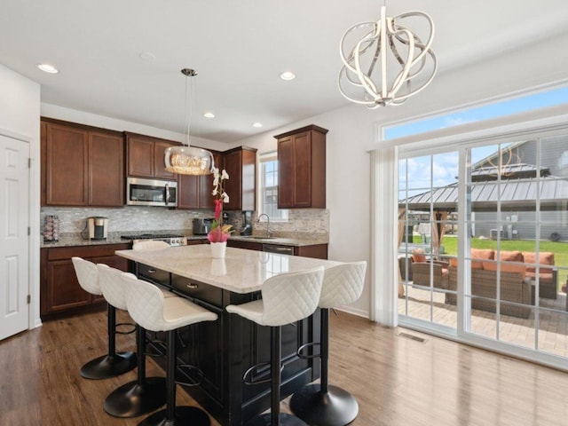 412 Towne Center Blvd, Shorewood, IL 60404 - kitchen featuring stainless steel appliances, light stone counters, dark wood-style flooring, decorative backsplash, and a kitchen island