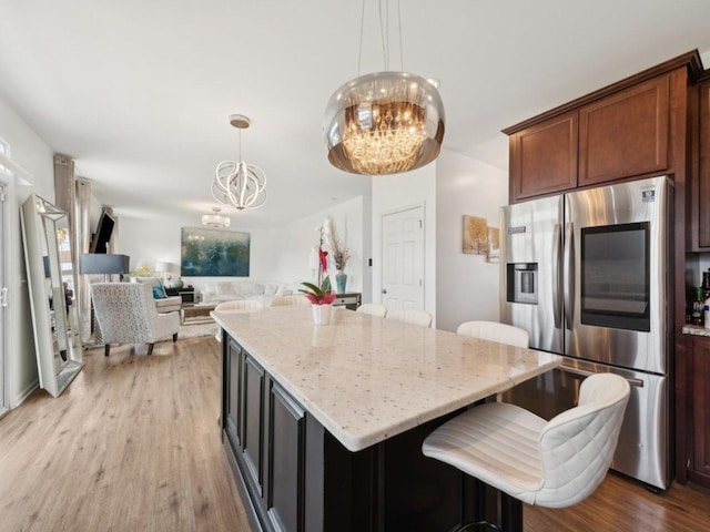412 Towne Center Blvd, Shorewood, IL 60404 - kitchen with a notable chandelier, a center island, light stone counters, light wood finished floors, and stainless steel fridge with ice dispenser