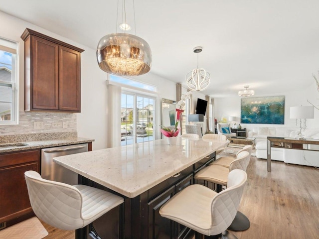 412 Towne Center Blvd, Shorewood, IL 60404 - kitchen with light wood finished floors, a kitchen breakfast bar, a notable chandelier, tasteful backsplash, and light stone counters
