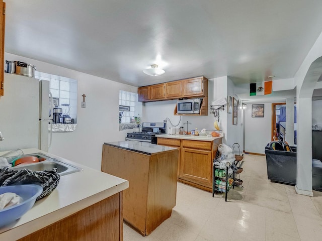 2936 N Kilpatrick Ave, Chicago, IL 60641 - kitchen with a center island, a sink, brown cabinetry, stainless steel appliances, and light countertops