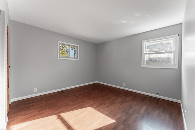 spare room featuring baseboards, wood finished floors, and visible vents
