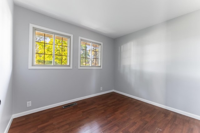 unfurnished room featuring plenty of natural light, baseboards, and dark wood-style flooring