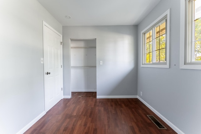 unfurnished bedroom featuring baseboards, wood finished floors, and visible vents
