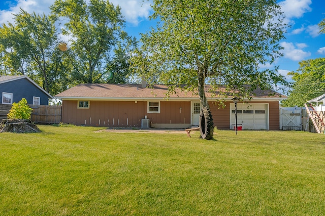 back of property with central air condition unit, a lawn, an attached garage, and fence