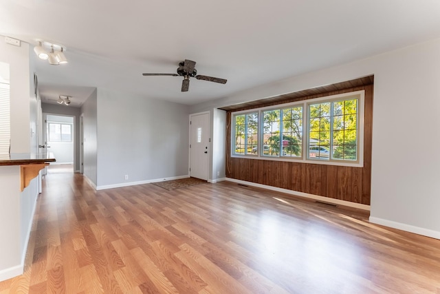 unfurnished living room featuring light wood-style floors, a ceiling fan, and baseboards