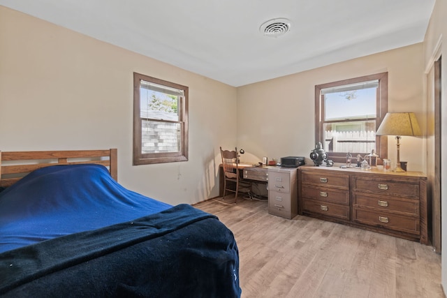 bedroom with light wood finished floors and visible vents