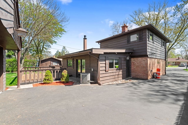 exterior space featuring brick siding, cooling unit, and a chimney