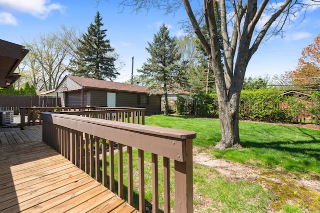 wooden terrace with a lawn, fence, and an outbuilding