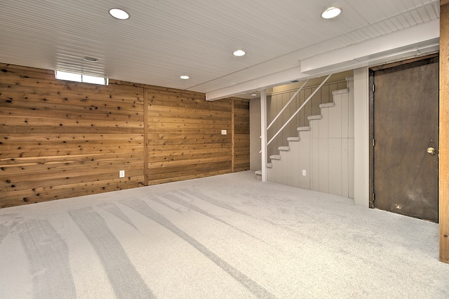 finished basement featuring recessed lighting, stairway, wood walls, and carpet