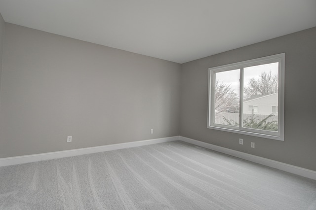 empty room featuring light colored carpet and baseboards