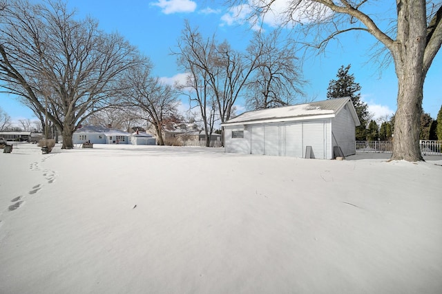 yard covered in snow featuring fence, an outbuilding, and a garage