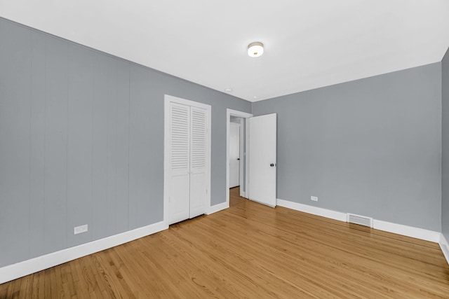 unfurnished bedroom featuring a closet, light wood-style flooring, visible vents, and baseboards