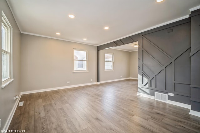 unfurnished living room with wood finished floors, visible vents, crown molding, and baseboards