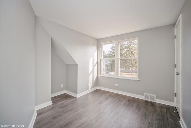 bonus room with wood finished floors, visible vents, and baseboards