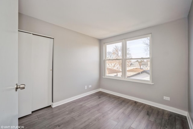 unfurnished bedroom with baseboards, wood finished floors, and a closet
