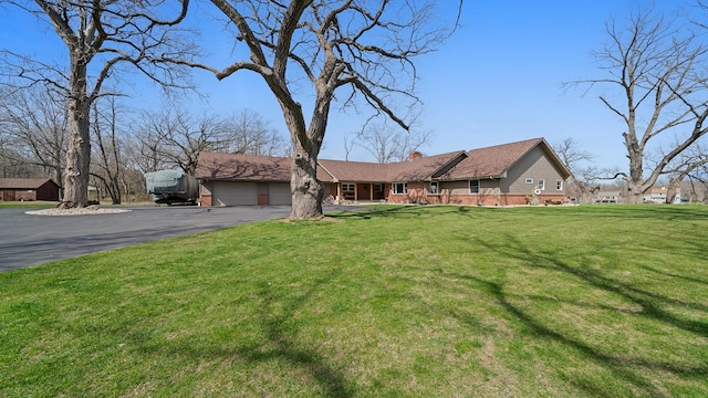 ranch-style house with a chimney, a front lawn, aphalt driveway, and a garage