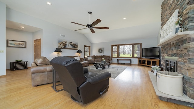 living area with light wood finished floors, vaulted ceiling, visible vents, ceiling fan, and a fireplace