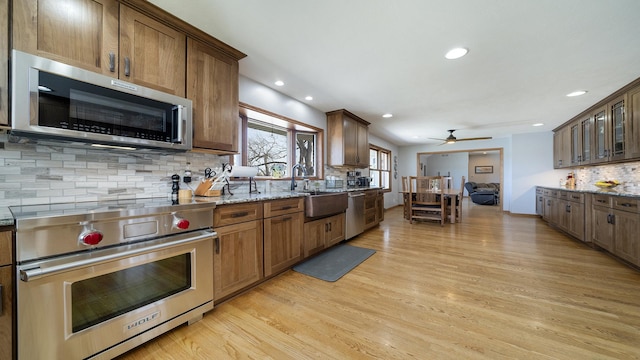kitchen with tasteful backsplash, stainless steel appliances, light wood-style floors, and a sink