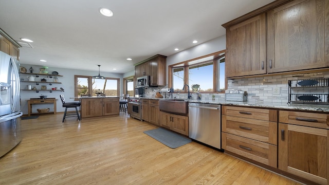 kitchen featuring recessed lighting, light wood finished floors, stainless steel appliances, backsplash, and a sink
