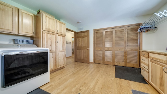 laundry area with cabinet space, light wood-style floors, and visible vents