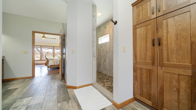 bathroom with wood finished floors, baseboards, walk in shower, ceiling fan, and ensuite bathroom