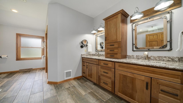 bathroom with wood finished floors, visible vents, baseboards, and a sink