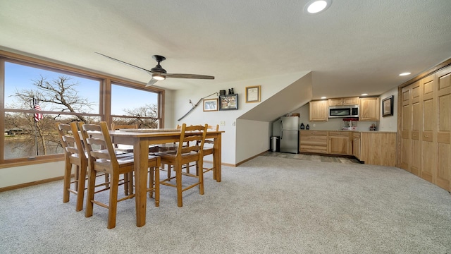dining room featuring baseboards, light colored carpet, and ceiling fan