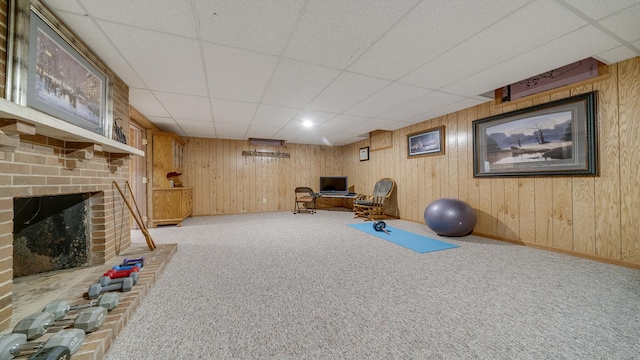 exercise room featuring a brick fireplace, carpet flooring, a drop ceiling, and baseboards