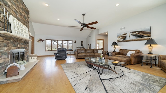 living room featuring vaulted ceiling, a ceiling fan, wood finished floors, a large fireplace, and visible vents