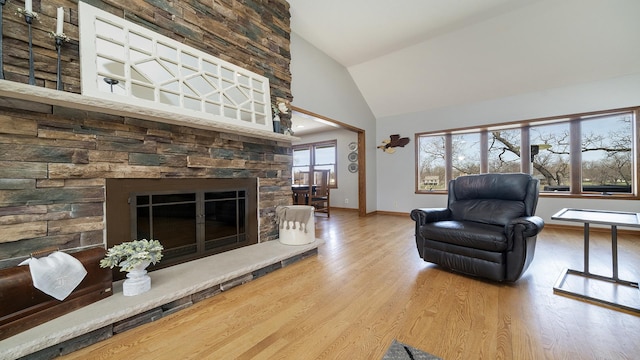 living area with a fireplace, baseboards, high vaulted ceiling, and wood finished floors