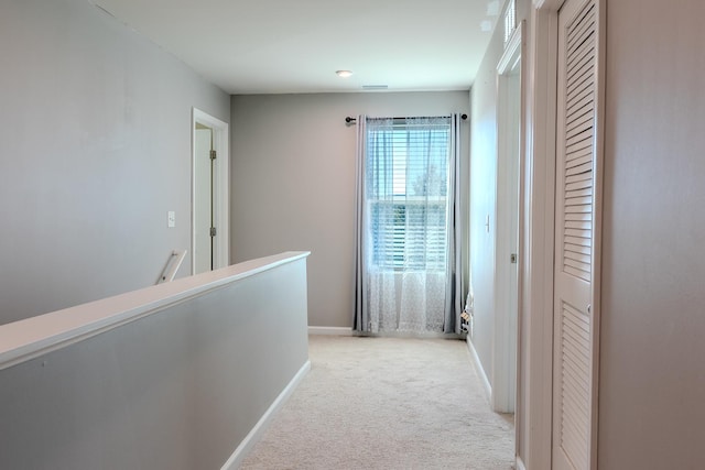 corridor with light carpet, baseboards, and an upstairs landing