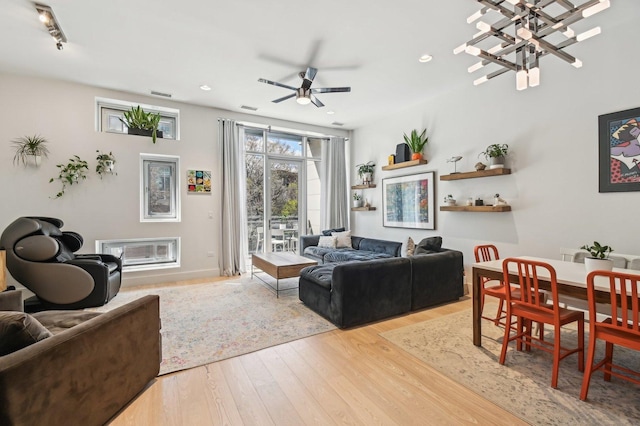 living room with ceiling fan with notable chandelier, recessed lighting, wood finished floors, and visible vents