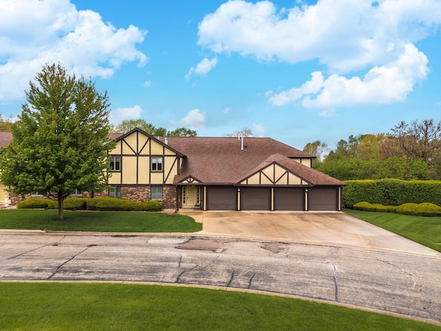tudor-style house featuring a front lawn, an attached garage, concrete driveway, and stucco siding