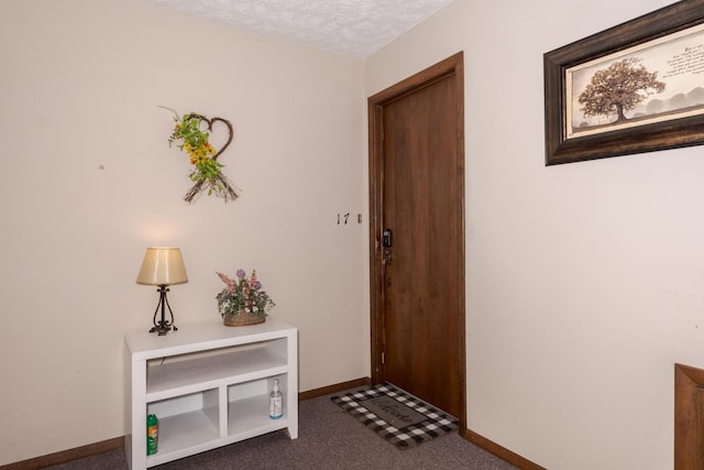 doorway with baseboards, dark carpet, and a textured ceiling