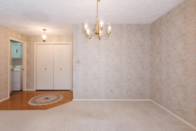 carpeted spare room featuring washer / clothes dryer, wallpapered walls, an inviting chandelier, and baseboards