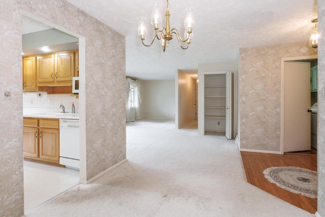 interior space featuring a sink, baseboards, an inviting chandelier, wallpapered walls, and white appliances