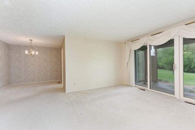 unfurnished room featuring visible vents, carpet flooring, baseboards, and a chandelier