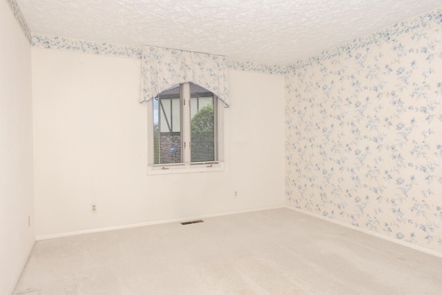 carpeted spare room featuring baseboards, wallpapered walls, a textured ceiling, and visible vents