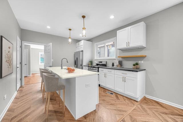 211 W 112th Pl, Chicago, IL 60628 - kitchen featuring an island with sink, baseboards, white cabinetry, and stainless steel appliances